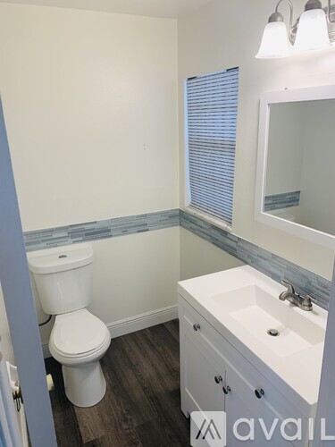 A white toilet sits in a bathroom with a white sink and a mirror.