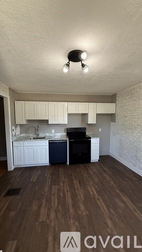 A kitchen with white cabinets and a black fridge.
