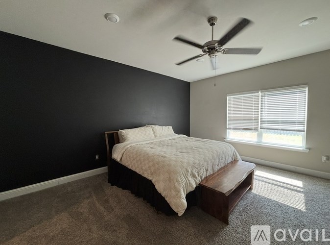 A bedroom with a bed, a ceiling fan, and a window with blinds.