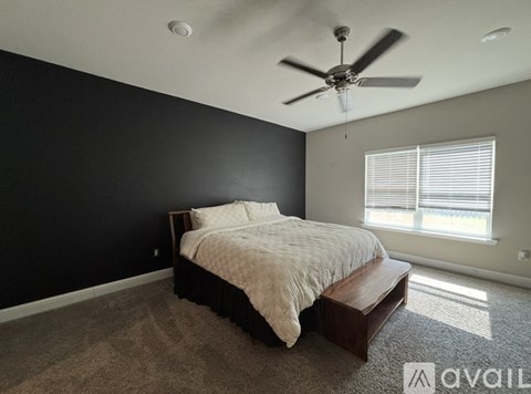 A bedroom with a bed, a ceiling fan, and a window with blinds.
