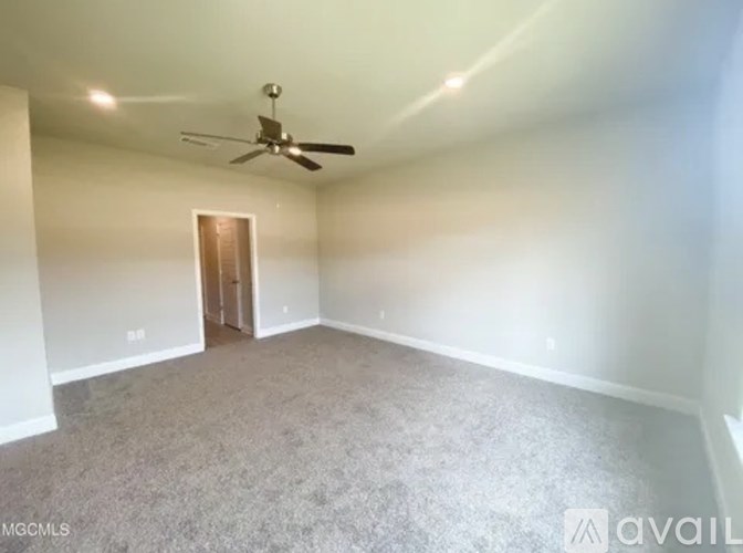 A spacious room with a ceiling fan and carpeted floor.