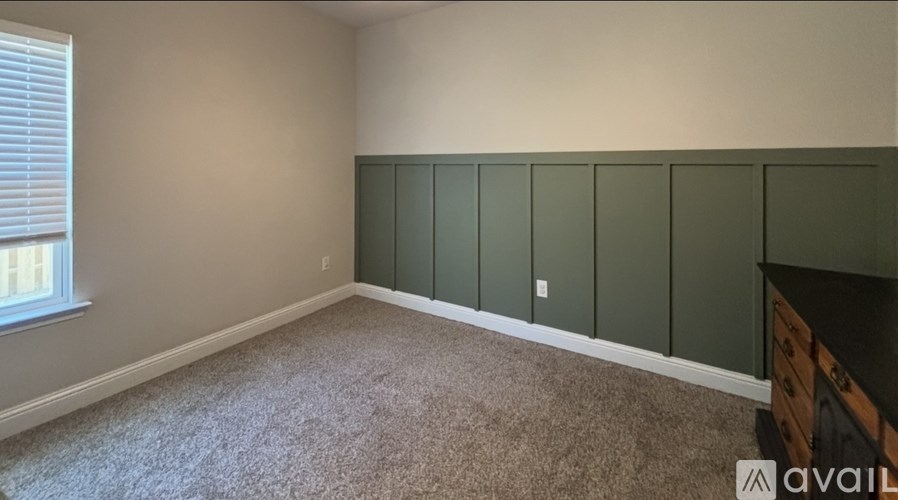 A room with a carpeted floor and a window with blinds.