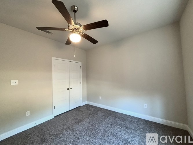 A room with a ceiling fan and carpeted floor.