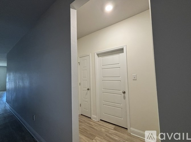 A hallway with two white doors and a light on the wall.