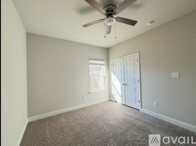 A room with a ceiling fan and a door leading to a balcony.