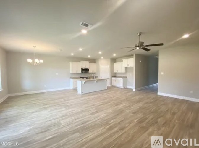 A spacious room with wooden flooring and a ceiling fan.
