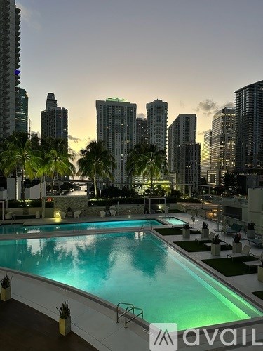 A large pool with a view of the city skyline at dusk.
