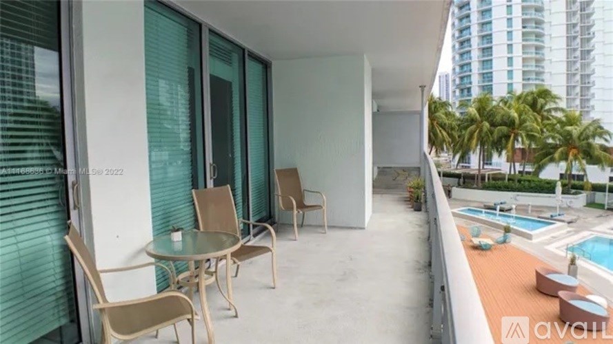 A balcony with a table and chairs overlooking a pool.