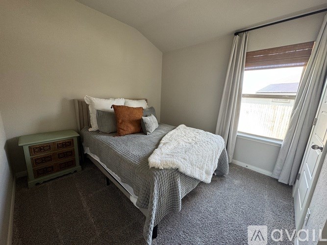A bedroom with a bed, nightstand, and window.