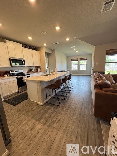 A kitchen with a white countertop and wooden flooring.