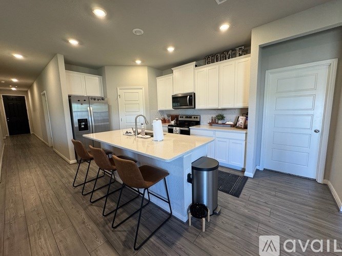 A kitchen with white cabinets and a large island with chairs.
