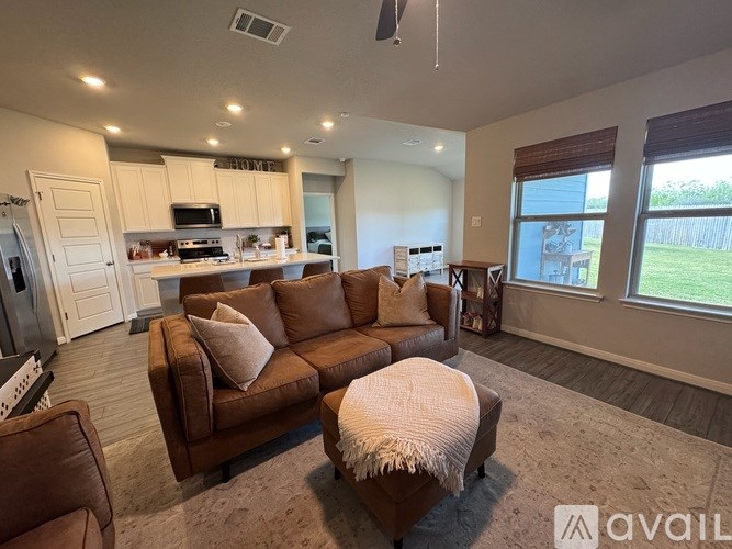 A living room with a brown couch and a white ottoman.