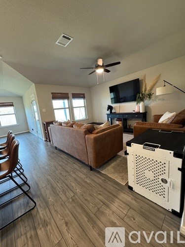 A living room with a brown couch and a television on a stand.