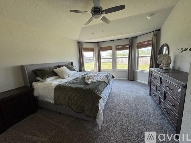 A bedroom with a large bed, a dresser, and a ceiling fan.