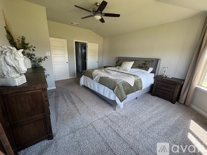 A bedroom with a bed, dresser, and ceiling fan.