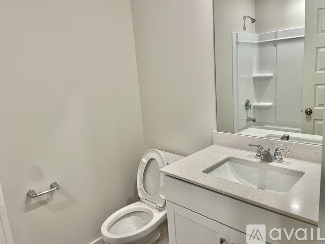 A white bathroom with a toilet, sink, and mirror.