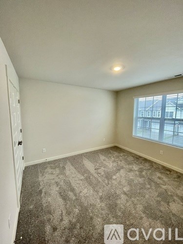 A room with a carpeted floor and a window showing a building outside.