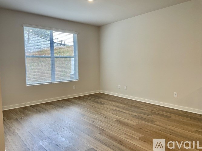 A room with wooden flooring and a window with blinds.