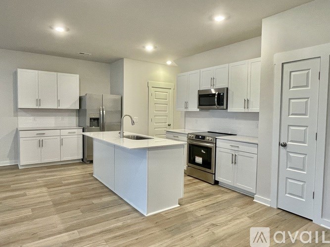 A kitchen with white cabinets and a wooden floor.