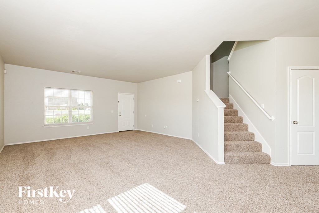 A spacious empty room with a staircase leading to the upper floor.