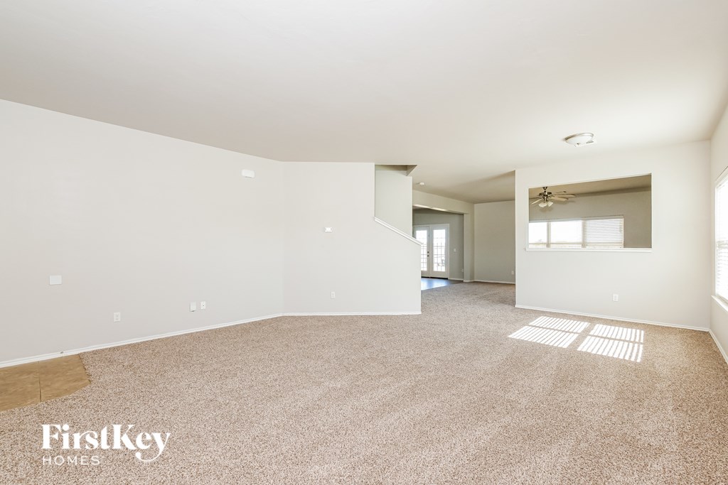 A spacious empty room with a carpeted floor and white walls.