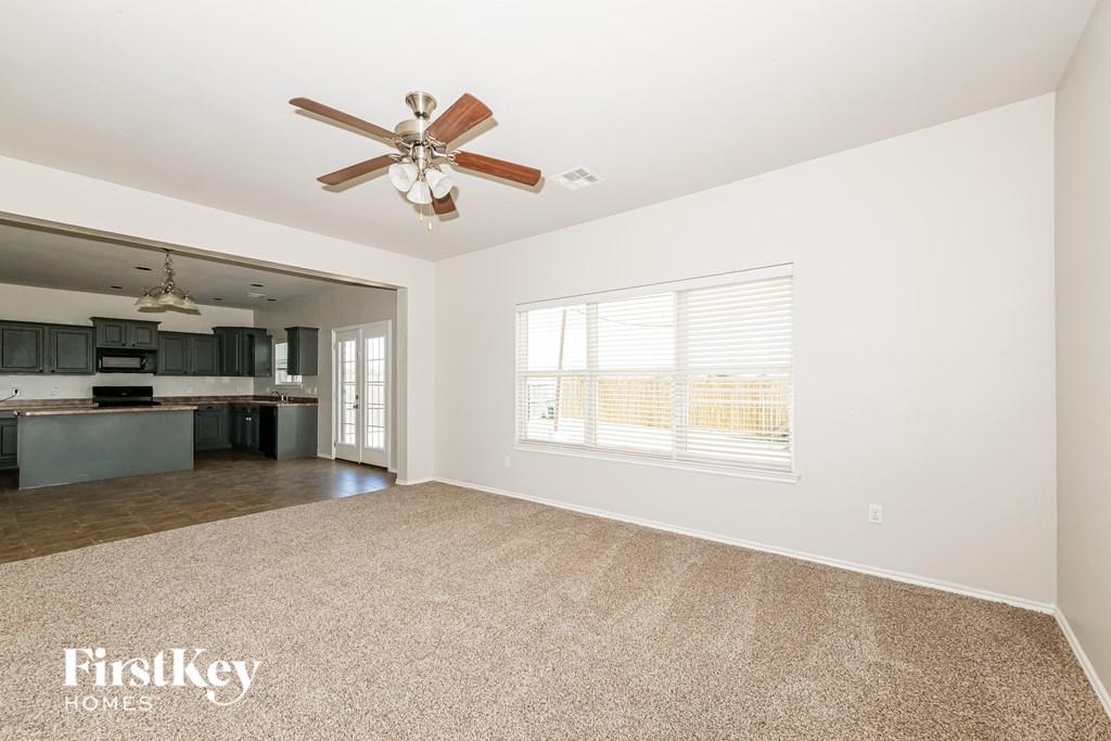 A spacious room with a ceiling fan and a carpeted floor.