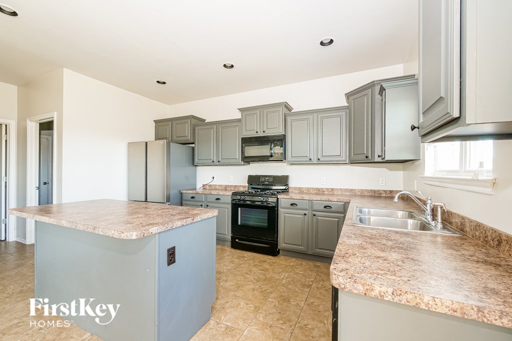 A kitchen with a granite countertop and a stove top oven.