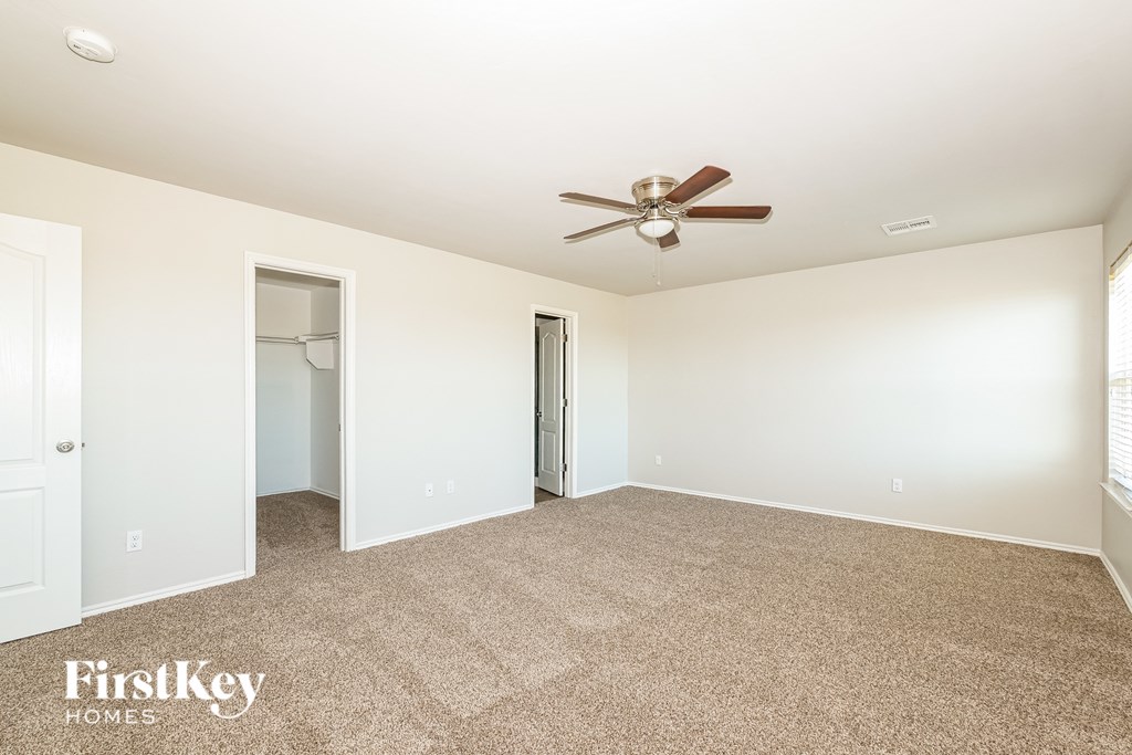 A carpeted room with a ceiling fan and two doors.