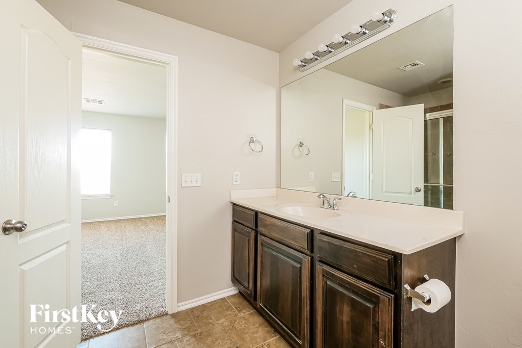 A bathroom with a white countertop and a mirror above it.