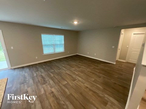 A room with wooden flooring and a window with blinds.