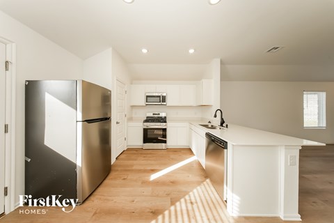 A kitchen with a refrigerator, microwave, oven, and sink.