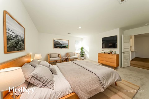 A bedroom with a large bed and a painting on the wall.