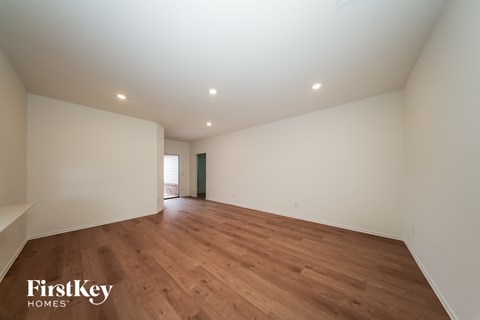 A spacious room with wooden flooring and white walls.