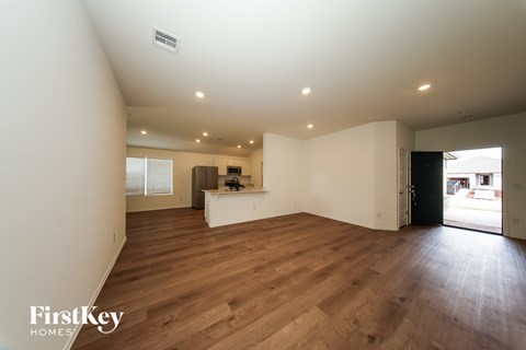 A spacious room with wooden floors and a kitchen area in the background.