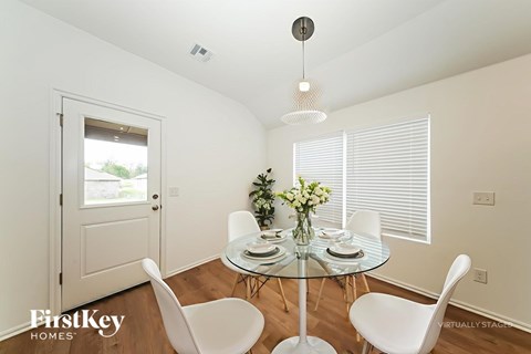 A dining room with a glass table and white chairs.
