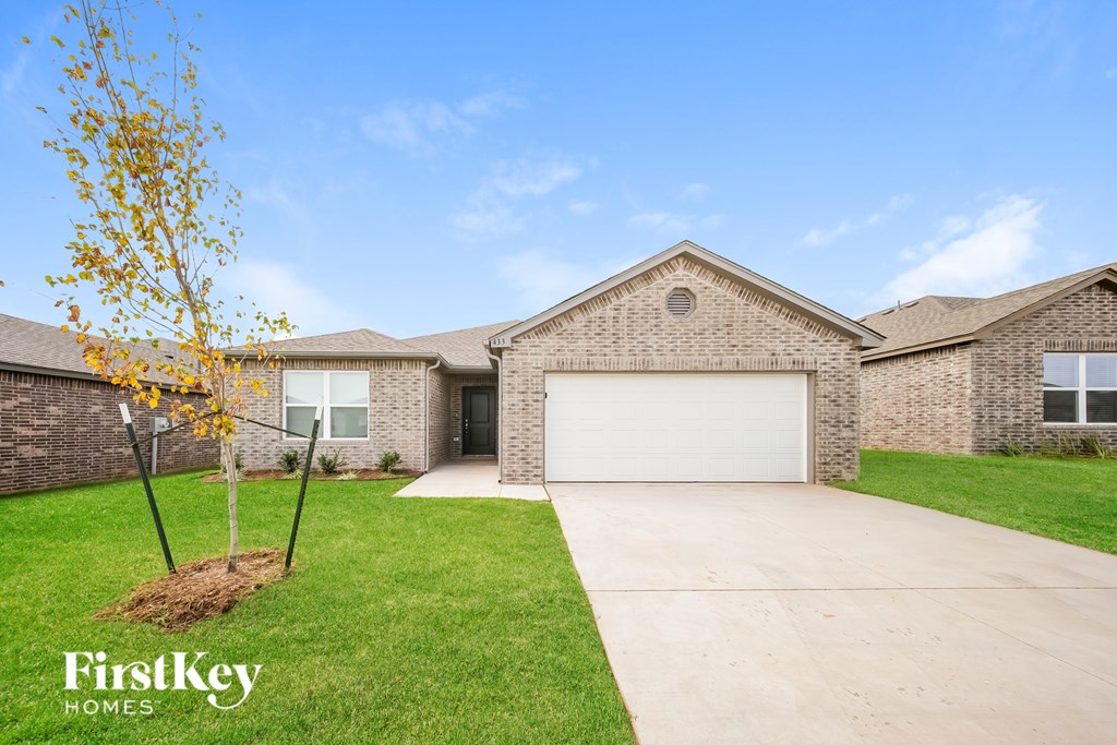 A house with a garage and a tree in front of it.