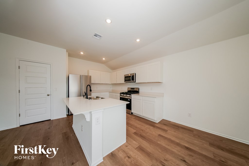 A kitchen with white cabinets and a wooden floor.