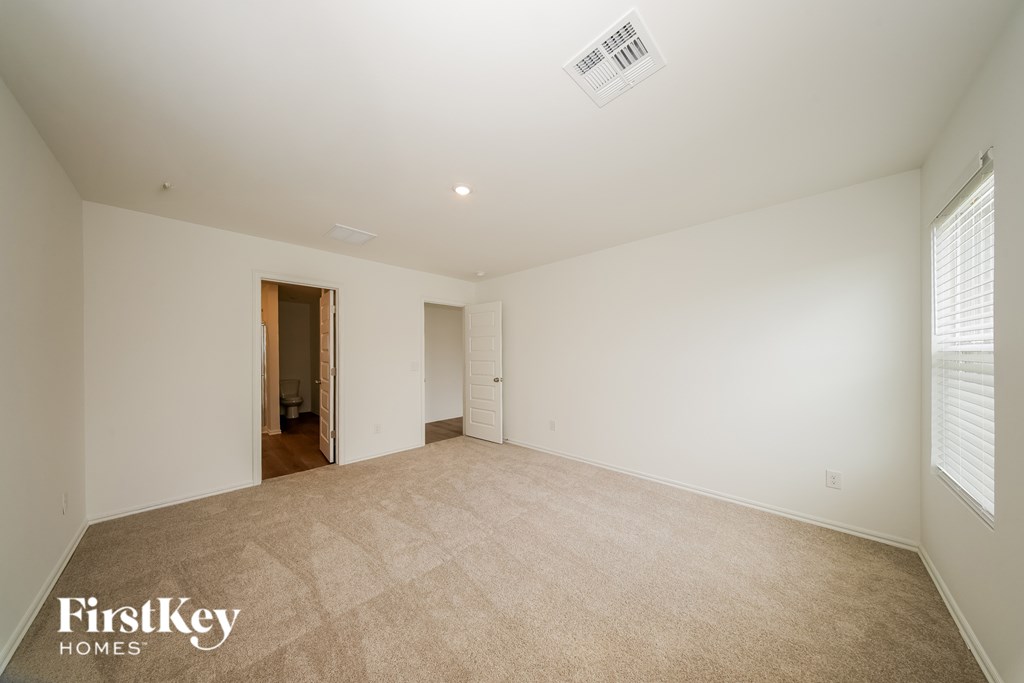 A spacious room with a carpeted floor and a doorway leading to another room.