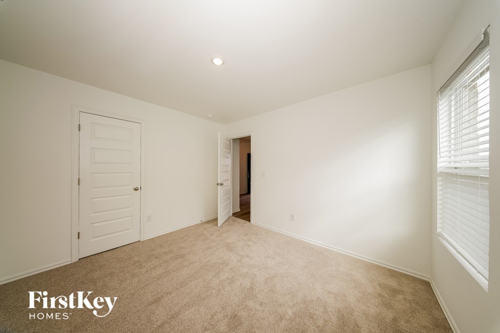 A room with a carpeted floor and a doorway leading to another room.