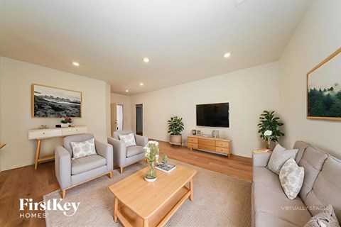 A living room with a grey couch, a wooden coffee table, and a painting on the wall.