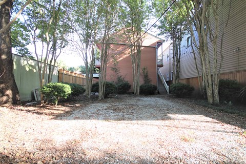 A backyard with a gravel ground and trees.