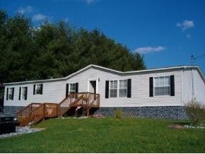 A white mobile home with a brown deck.