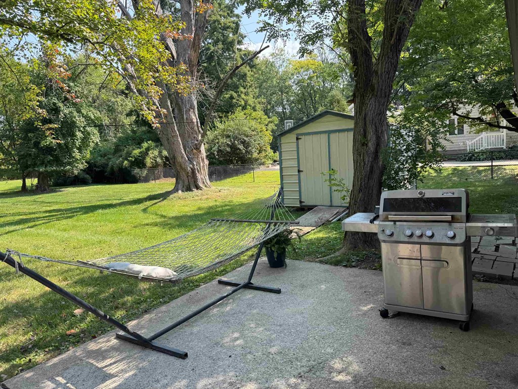 A backyard with a grill and a hammock.