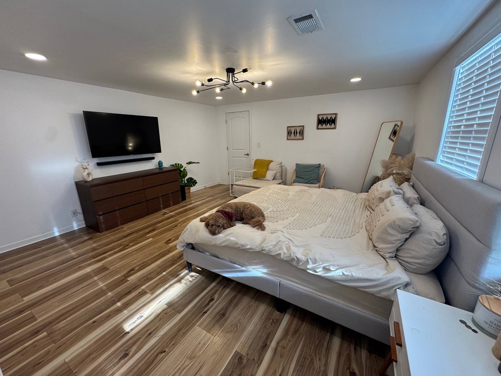 A dog is lying on a bed in a room with wooden flooring.
