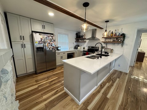 A kitchen with a white island and wooden floors.