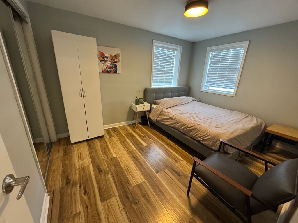 A bedroom with a bed, chair, and a painting on the wall.