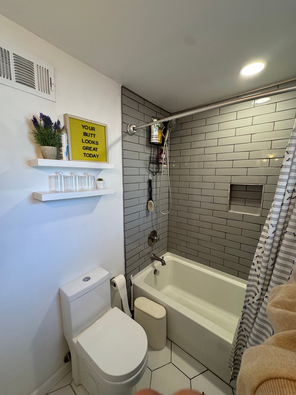 A bathroom with a toilet, a bathtub, and a sign on the wall.