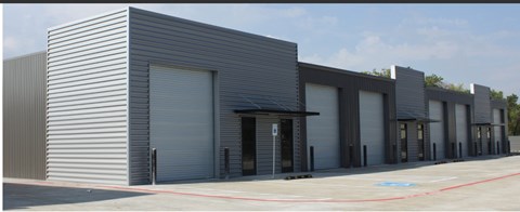 A building with grey walls and a grey roof with a black door.