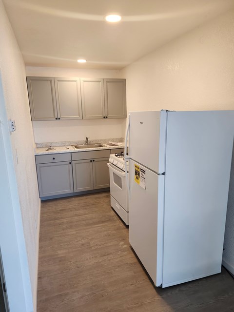 A kitchen with a white fridge and cabinets.
