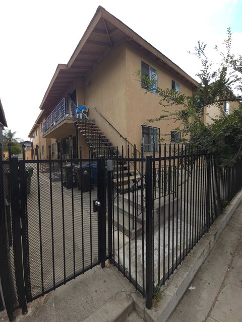 A black iron fence in front of a tan building.